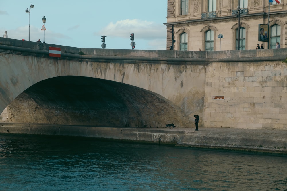 a man standing on the side of a bridge next to a body of water