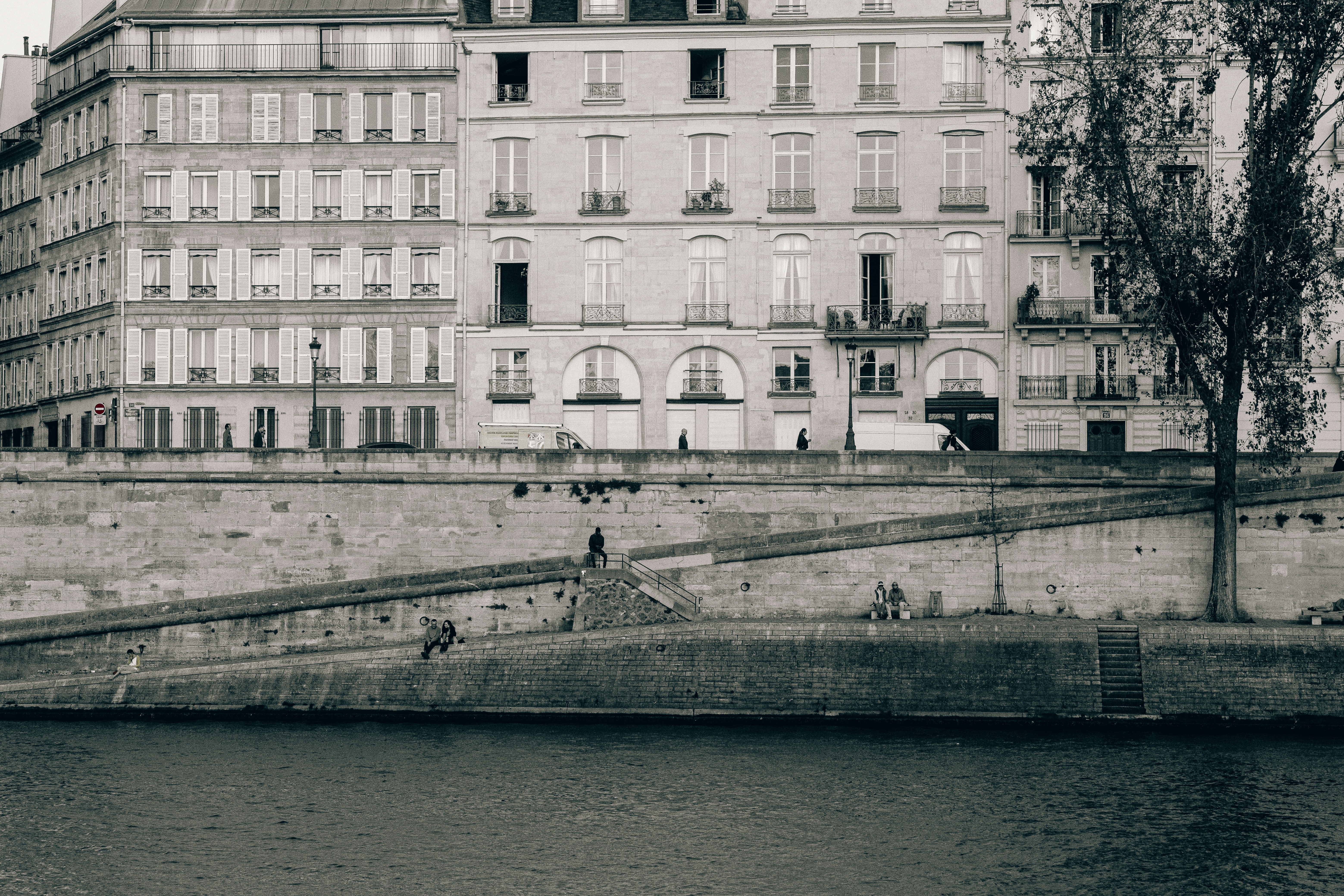 a black and white photo of a building next to a body of water, 