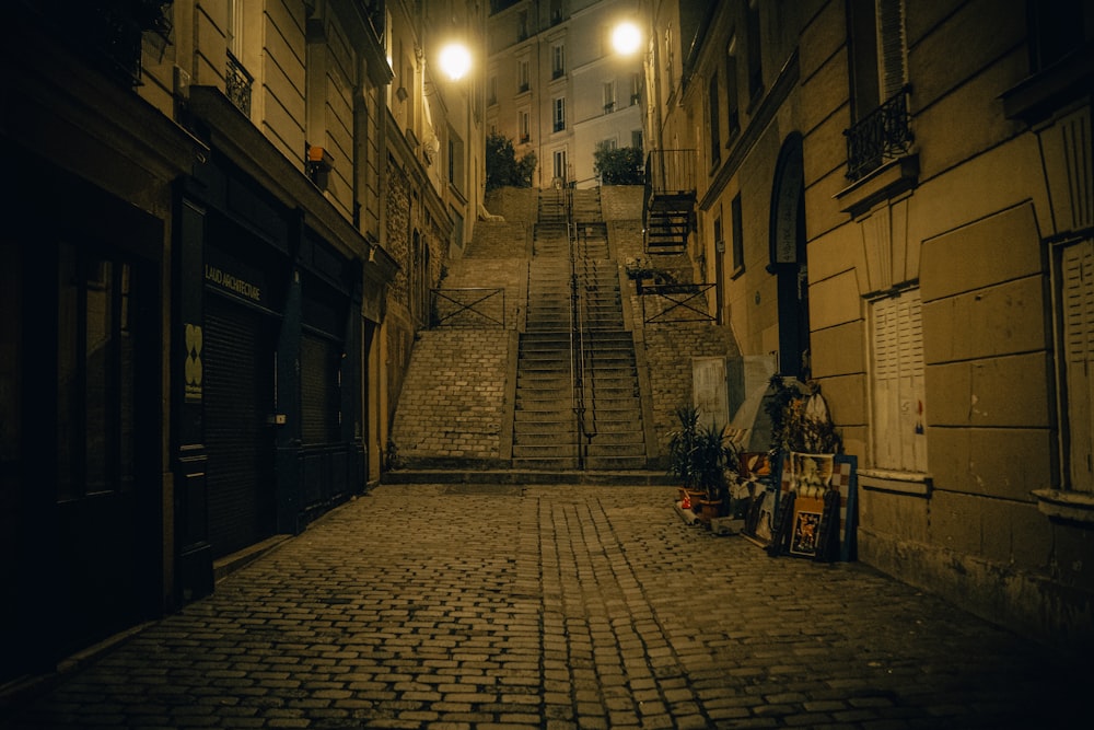 a cobblestone street at night with a set of stairs