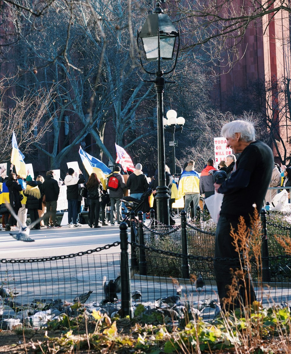 a man standing next to a fence near a crowd of people