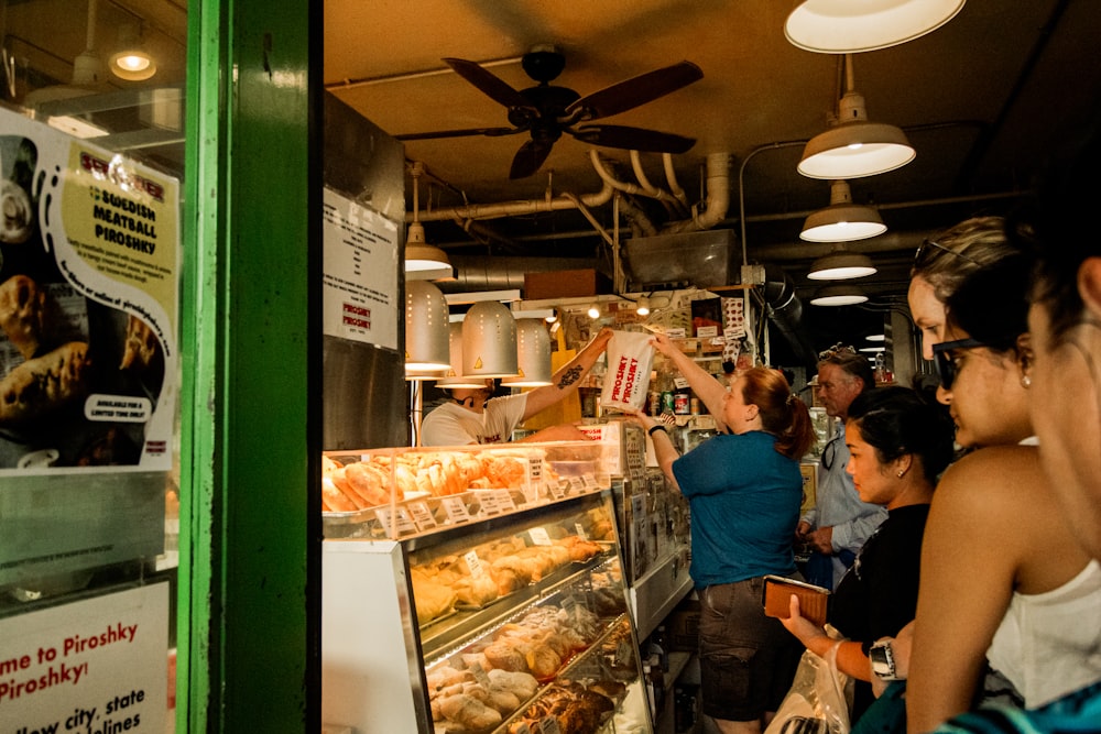 a group of people standing around a bakery