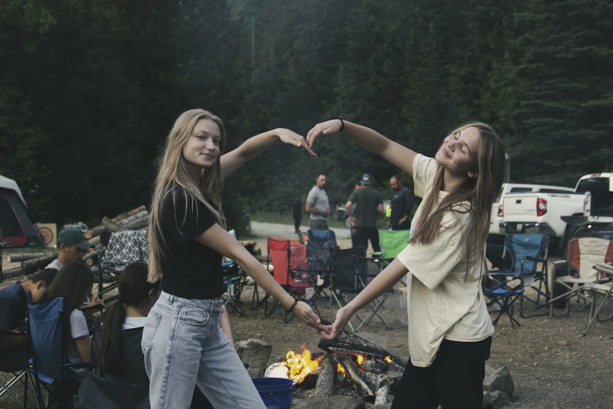 a couple of girls standing next to a fire