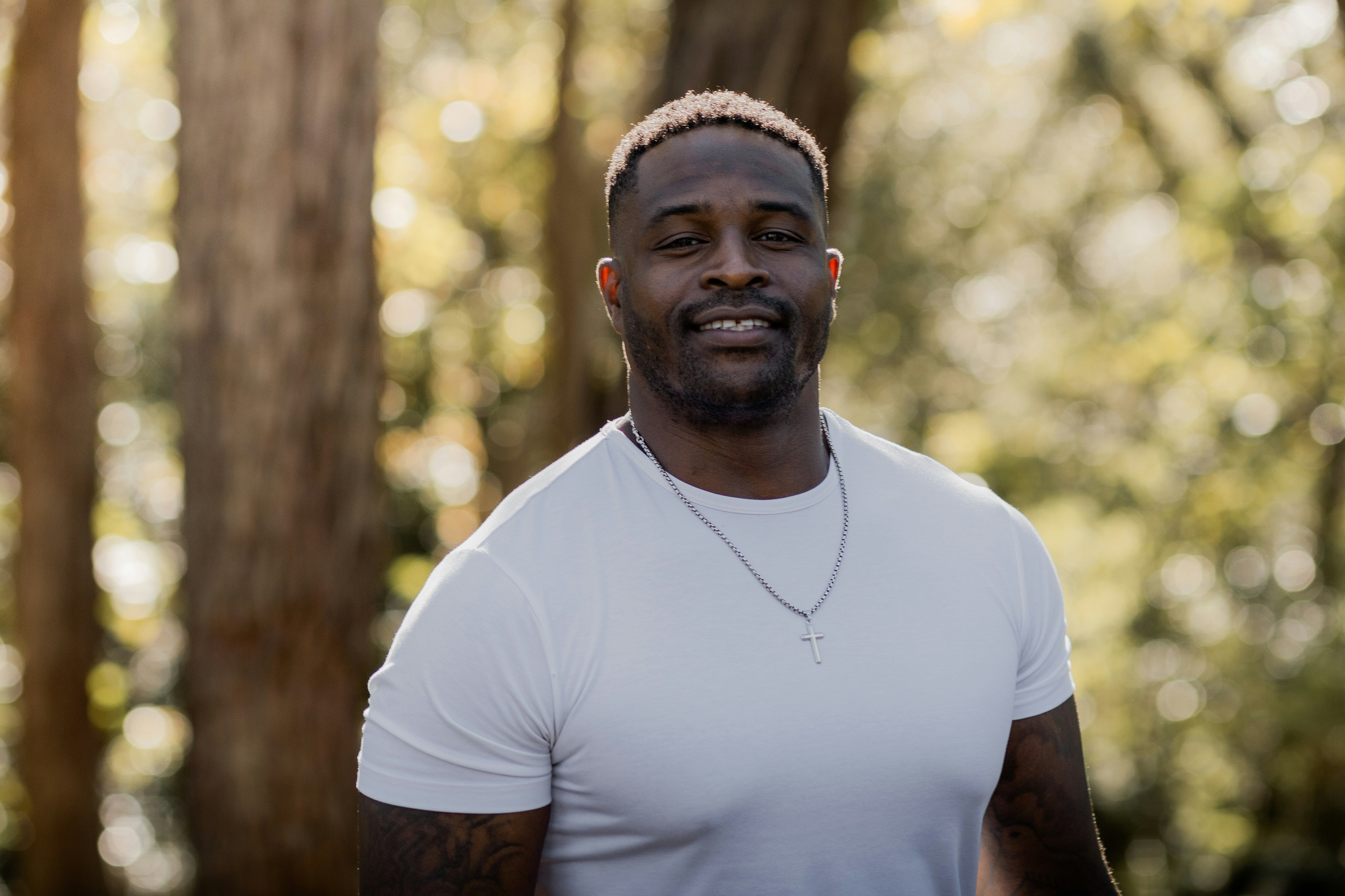 a man in a white shirt standing in front of trees