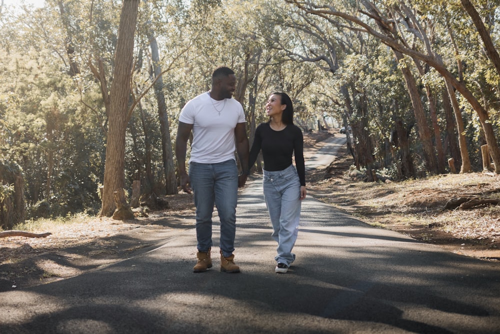 a man and a woman walking down a tree lined road