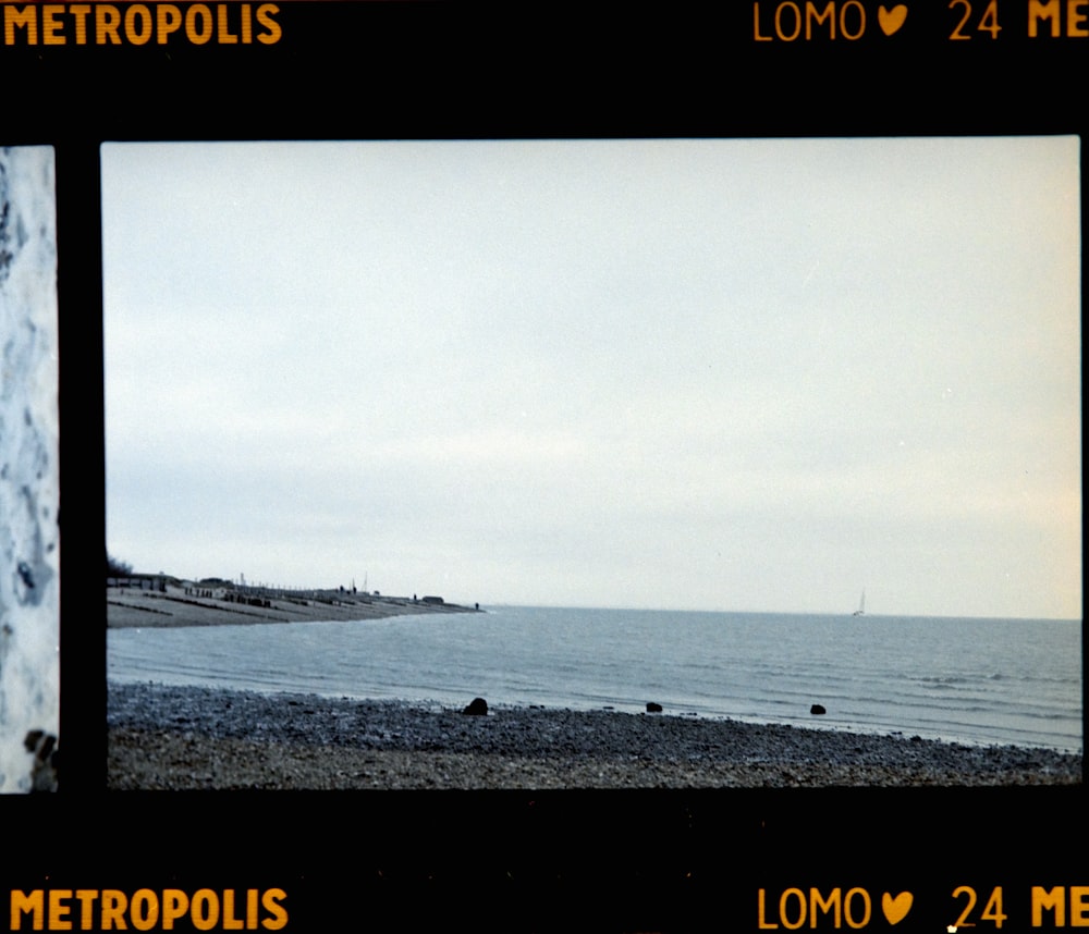 a polaroid picture of a beach with a boat in the distance
