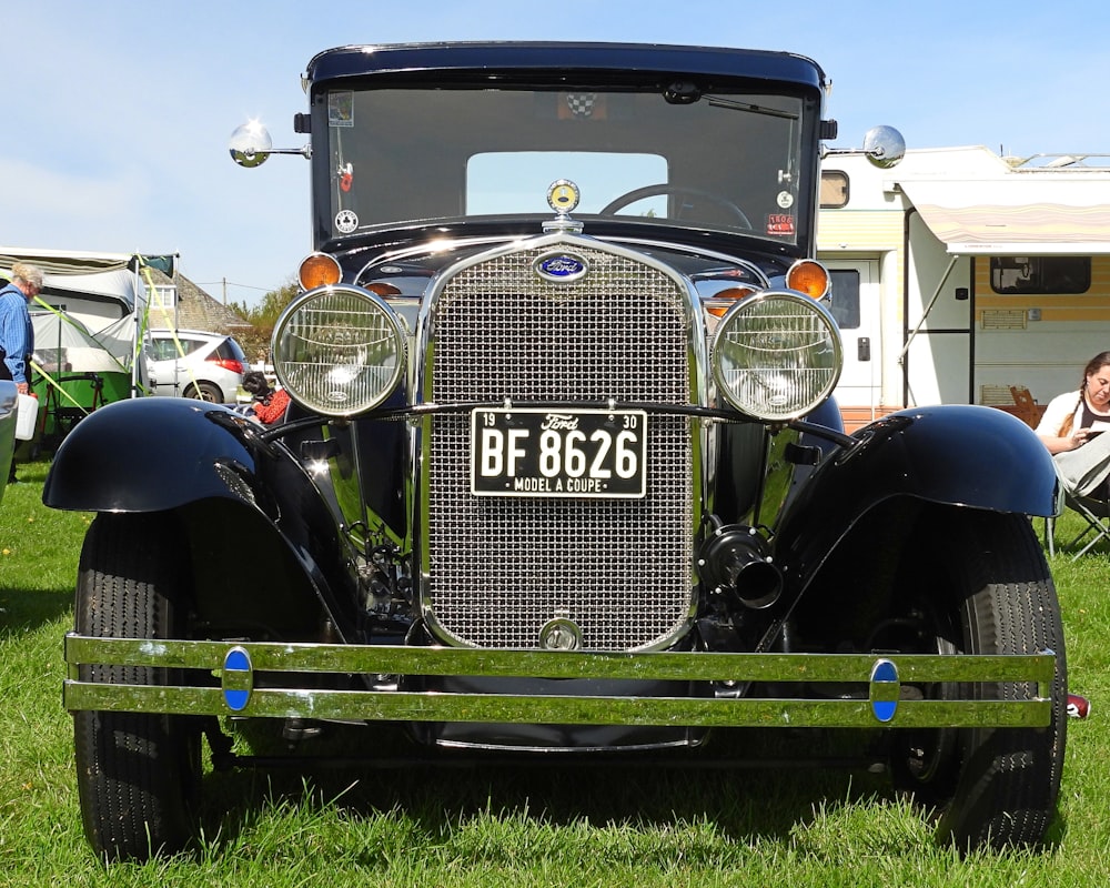 an antique car is parked in the grass