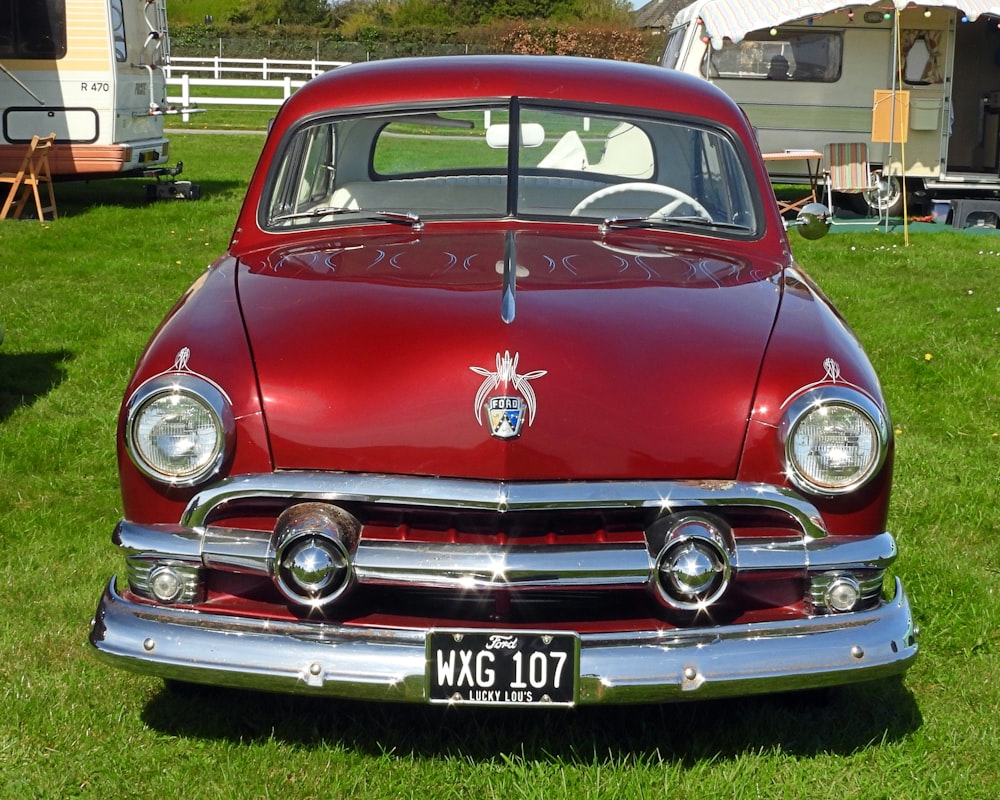 an old red car is parked in the grass