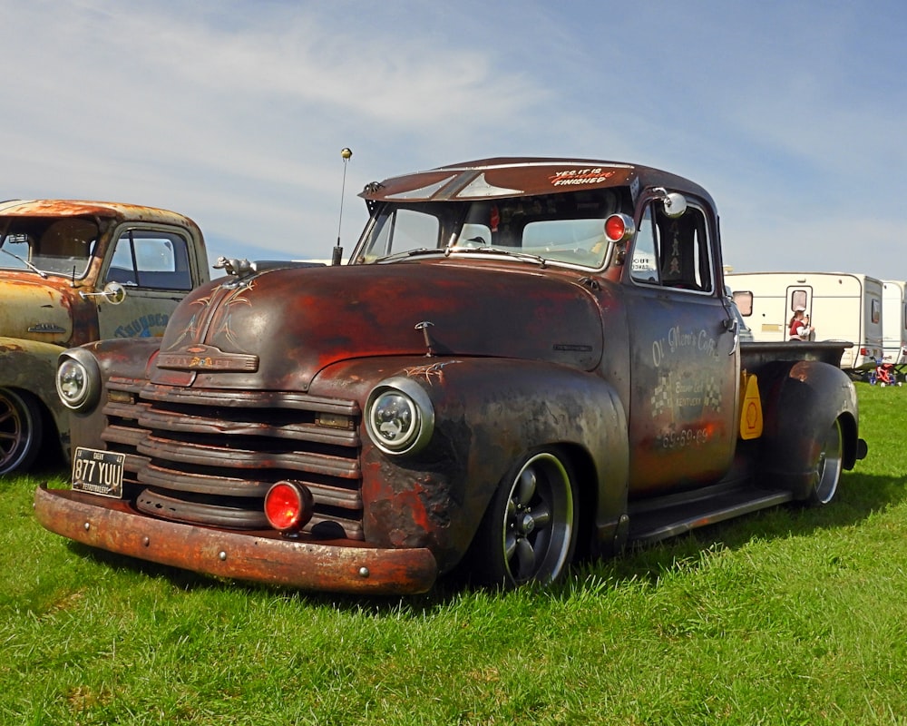 two old trucks are parked in the grass
