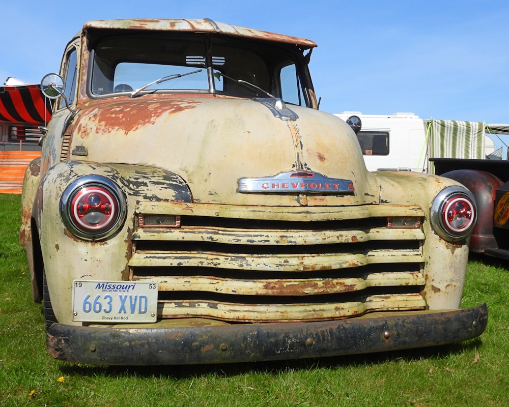 an old truck is parked in the grass