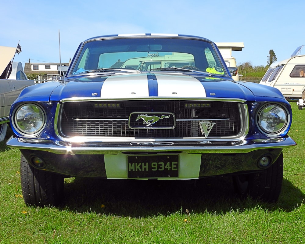 a blue and white mustang parked in the grass
