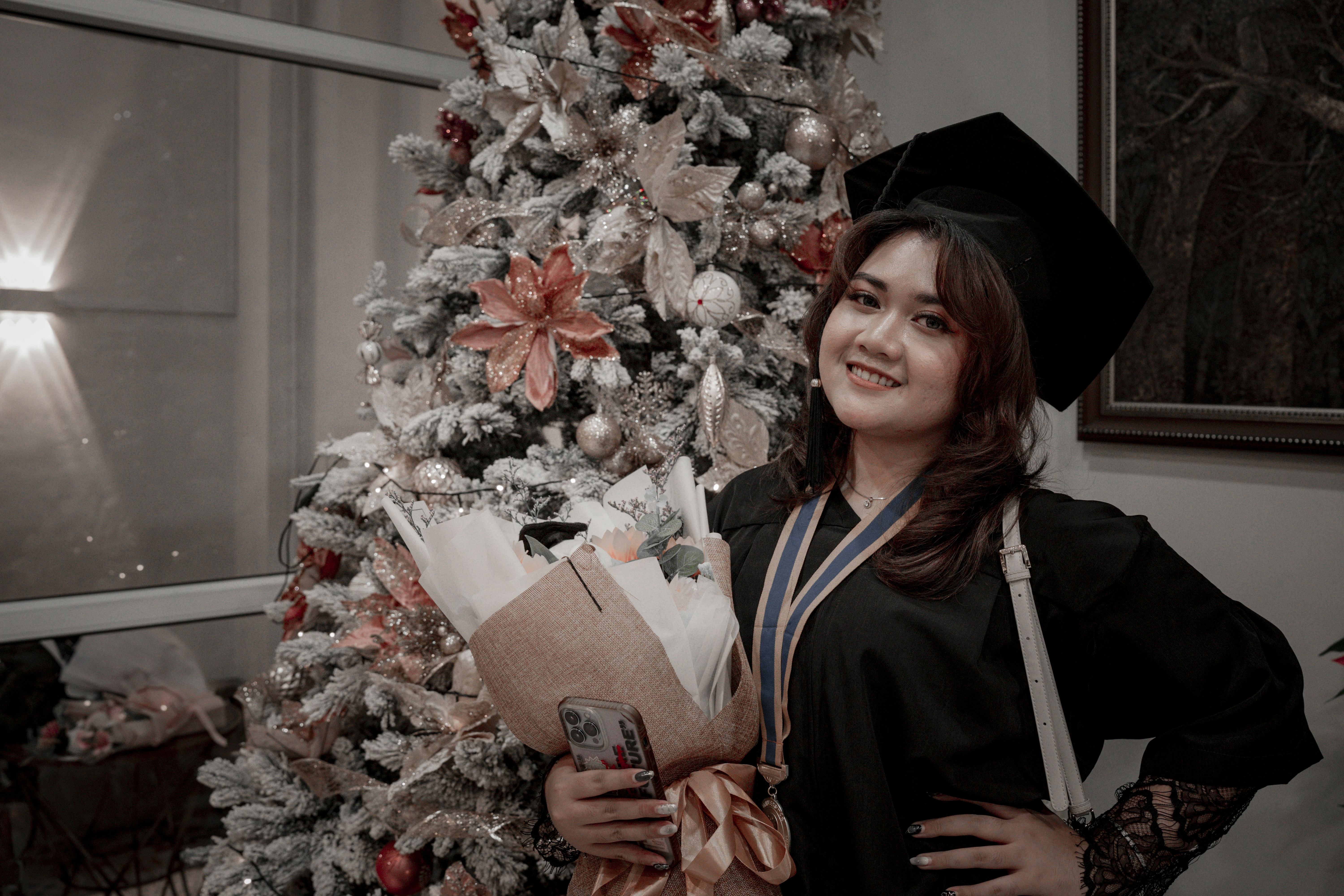 a woman in a graduation gown holding a bouquet of flowers