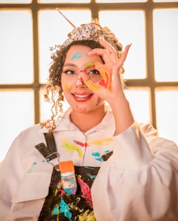 a woman wearing a crown and holding her hands up to her face