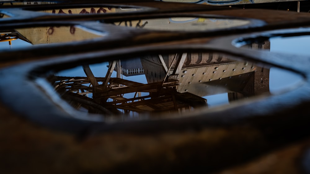 a reflection of a bridge in a puddle of water