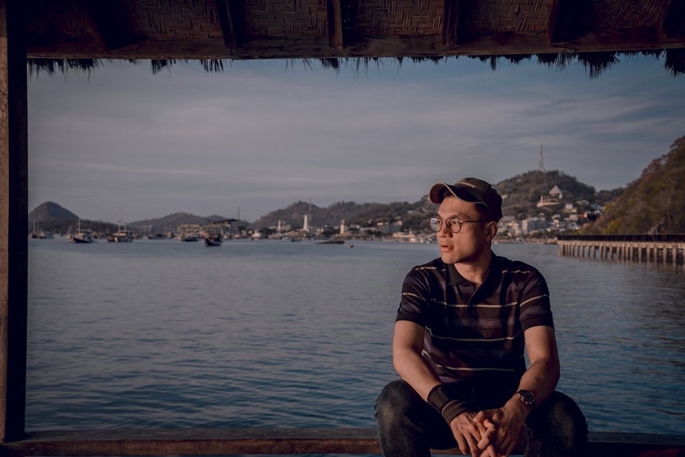 a man sitting on a dock looking out at the water