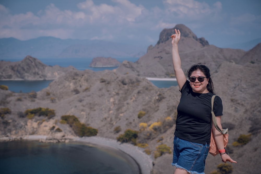 a woman with her arms in the air on top of a mountain