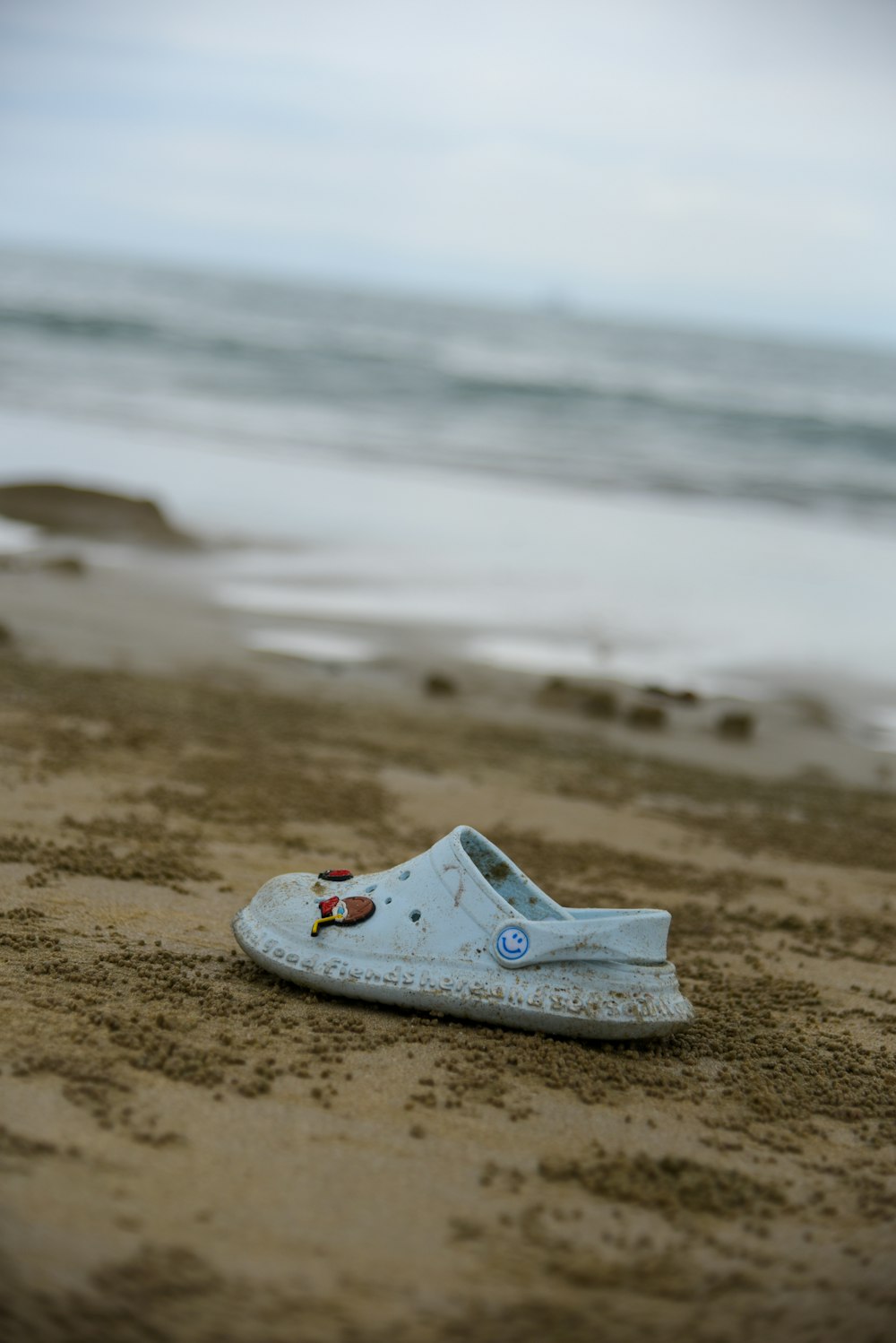 a pair of white shoes sitting on top of a sandy beach