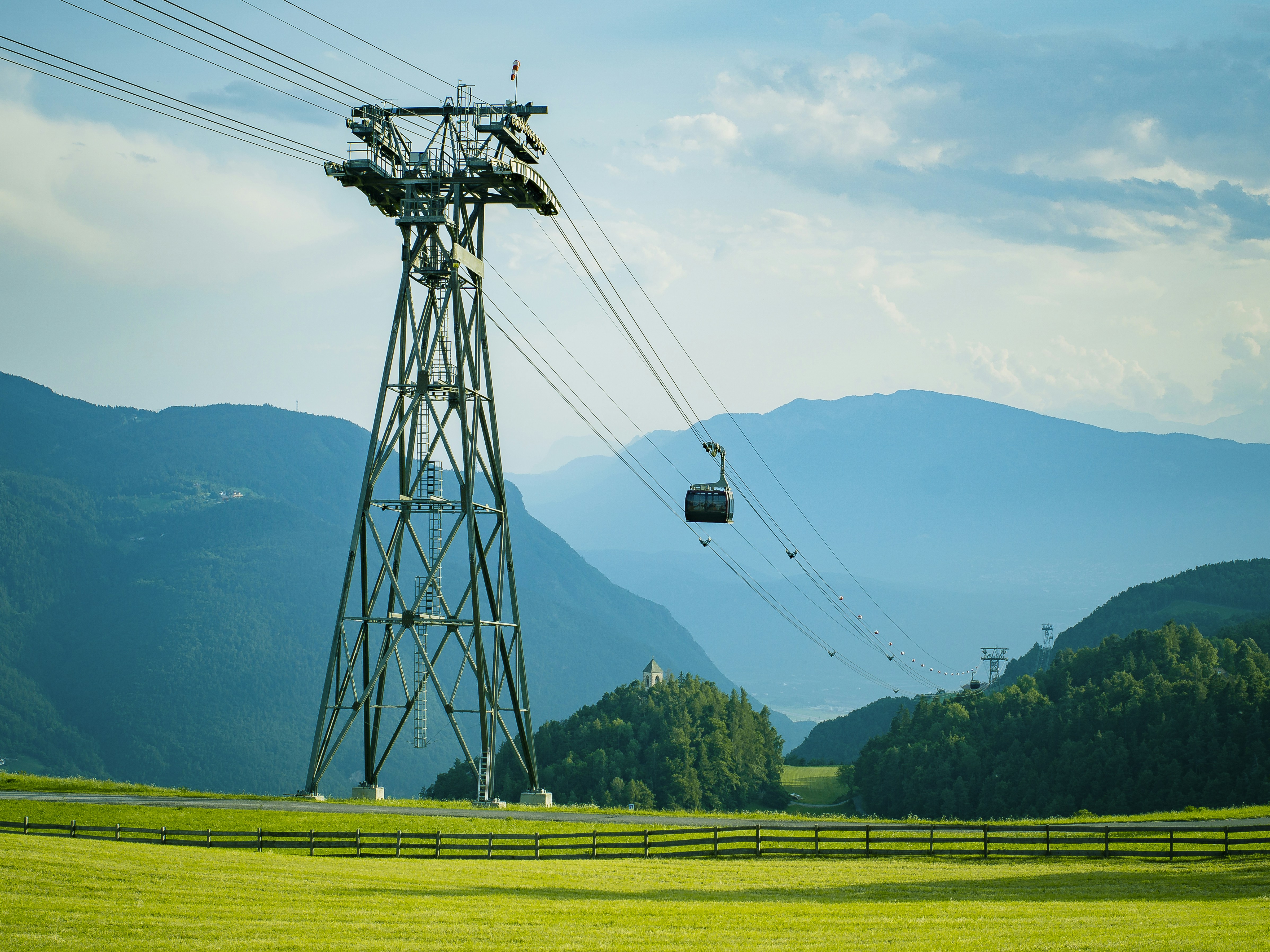 a cable car going over a lush green hillside
