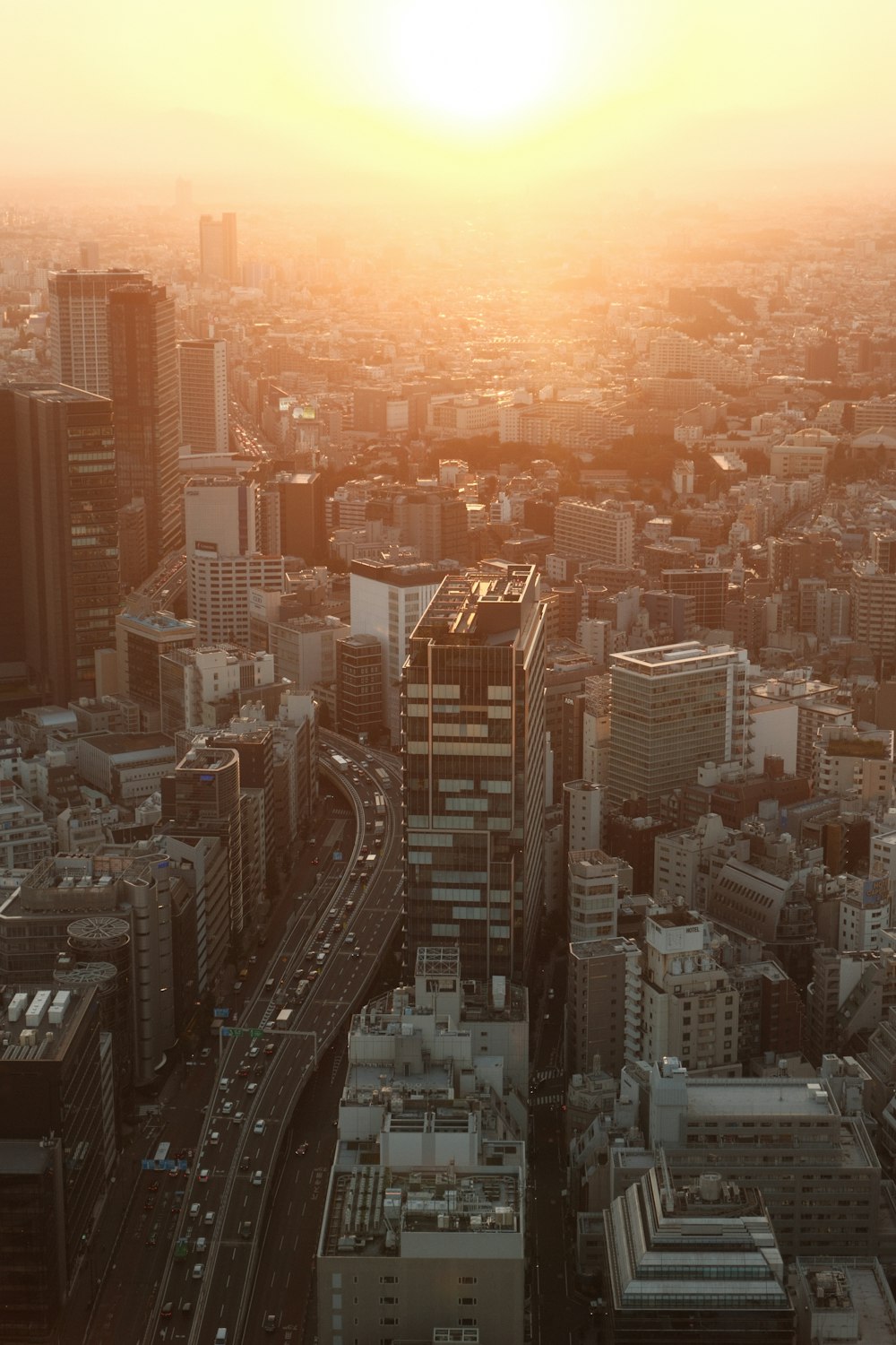 the sun is setting over a city with tall buildings