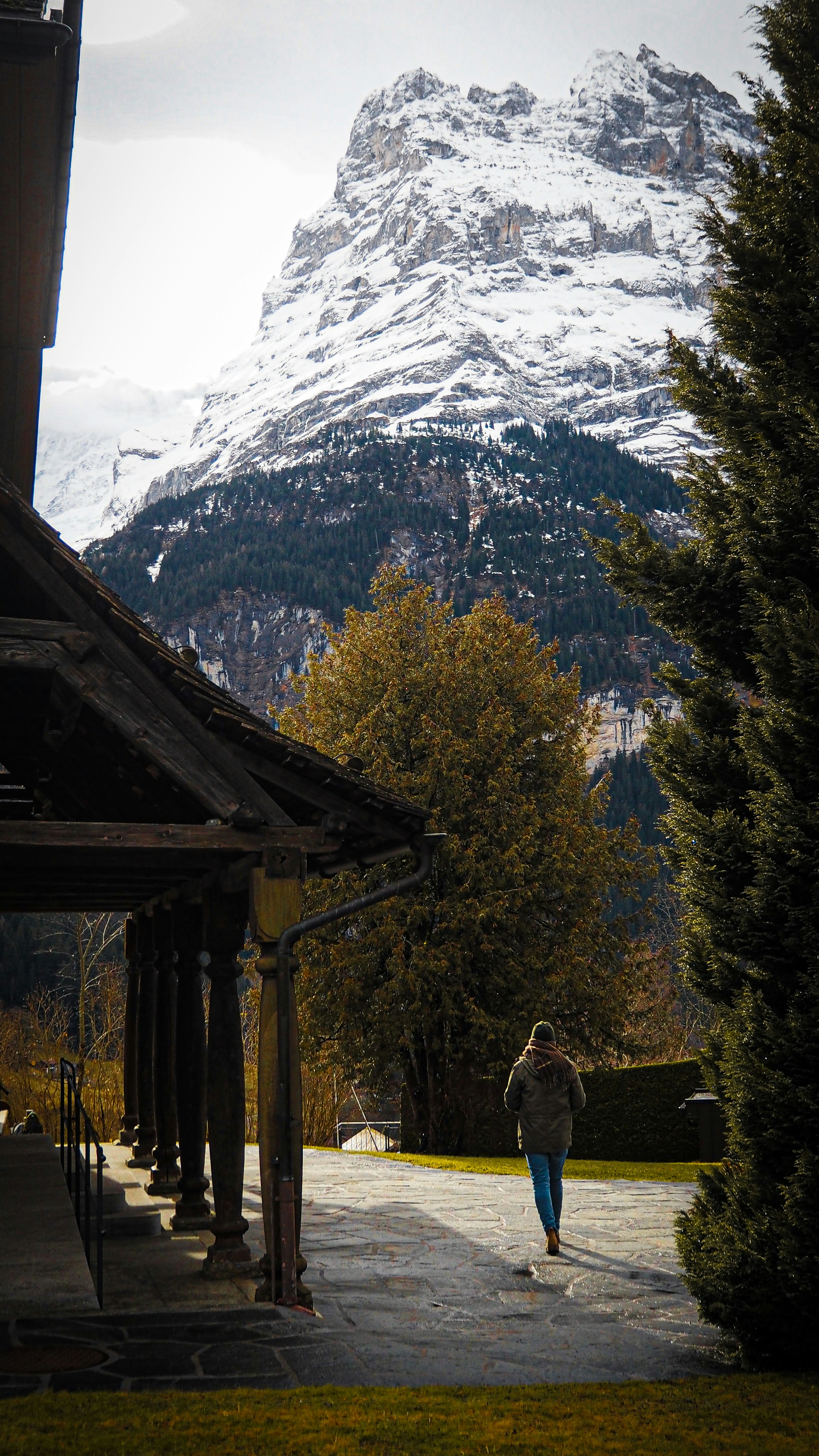 a person walking down a walkway in front of a snow covered mountain