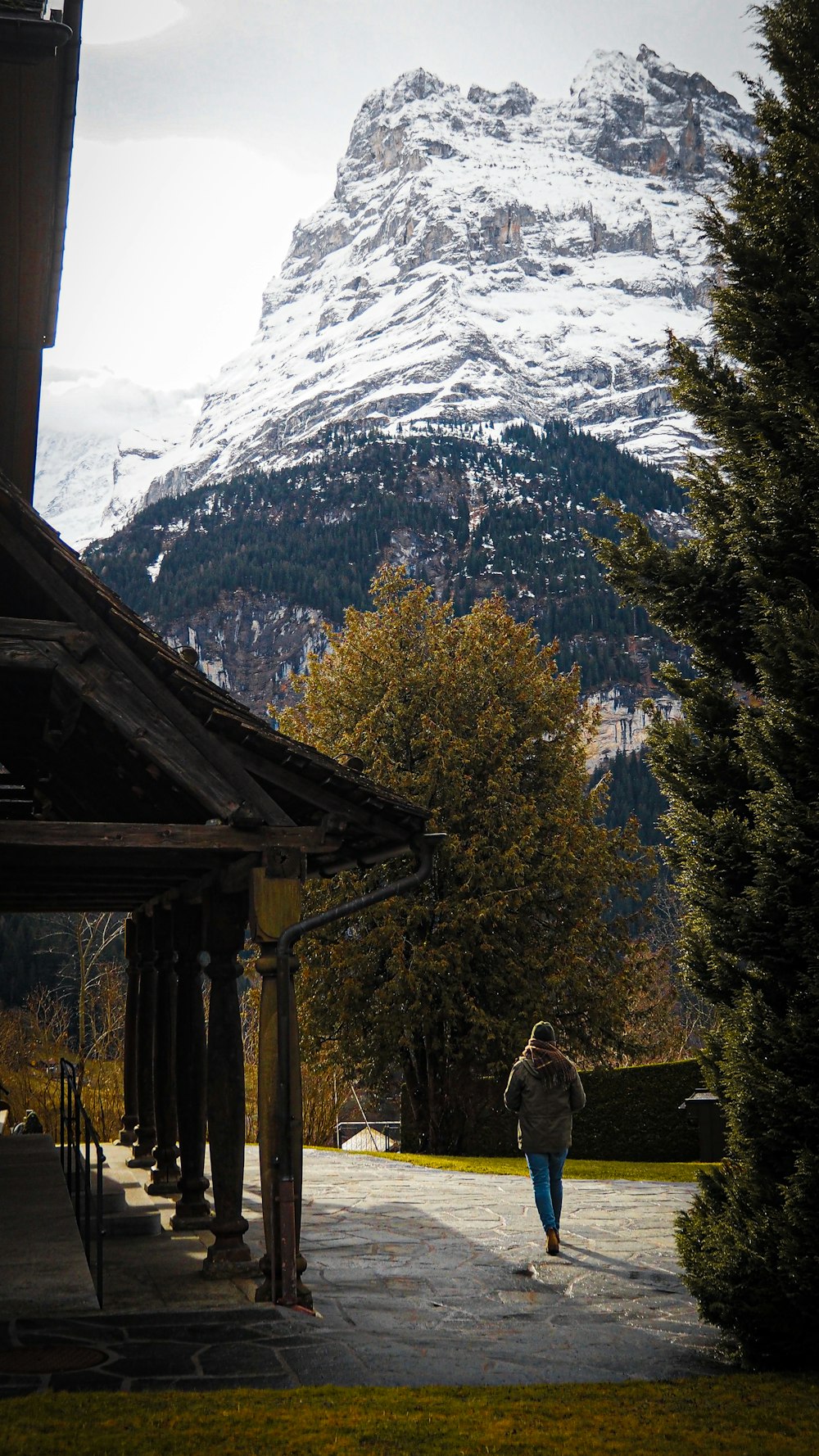 a person walking down a walkway in front of a snow covered mountain