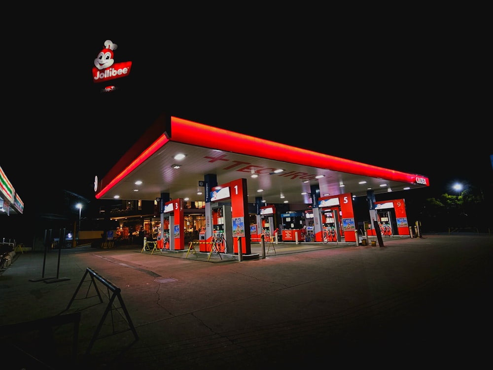 a gas station at night with a lit up sign