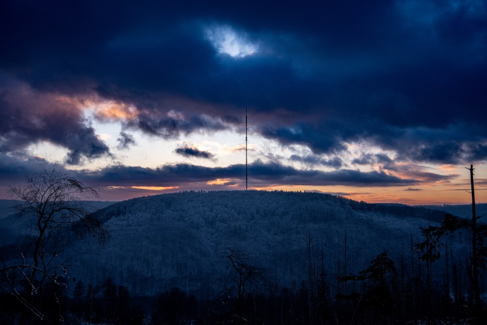 the sun is setting over a mountain with a tower in the distance