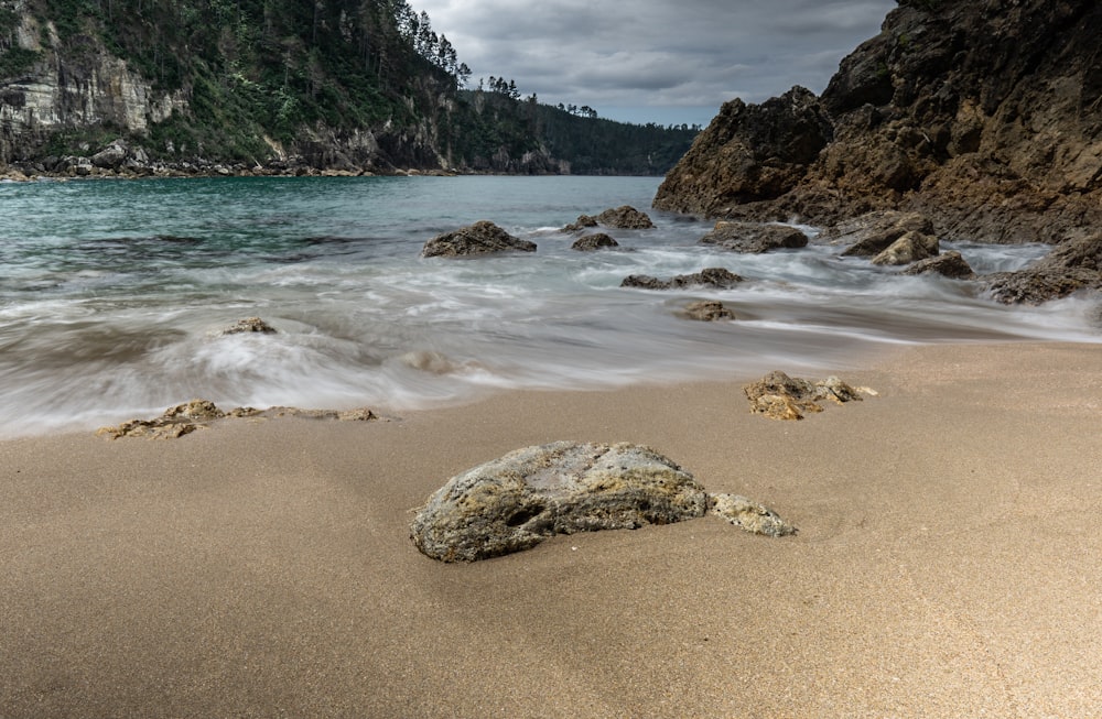 a rock on a sandy beach next to the ocean