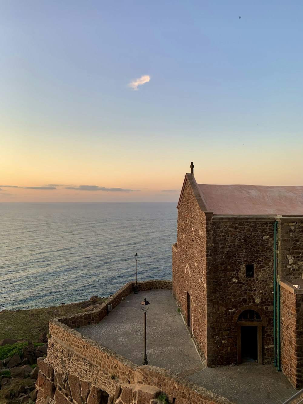 a stone building sitting on top of a cliff next to the ocean