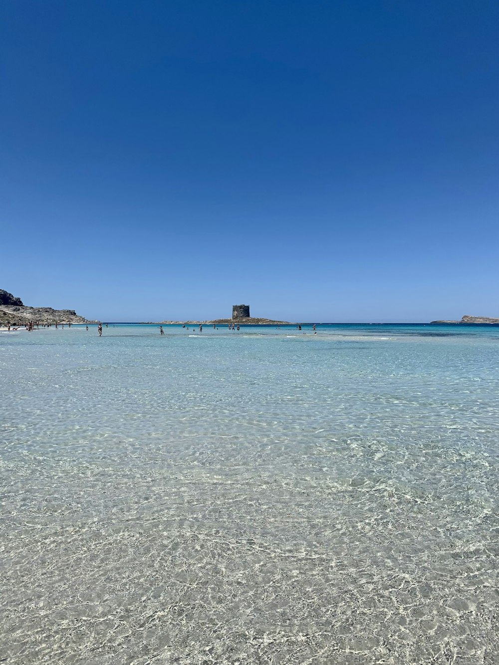 a sandy beach with clear blue water and a blue sky