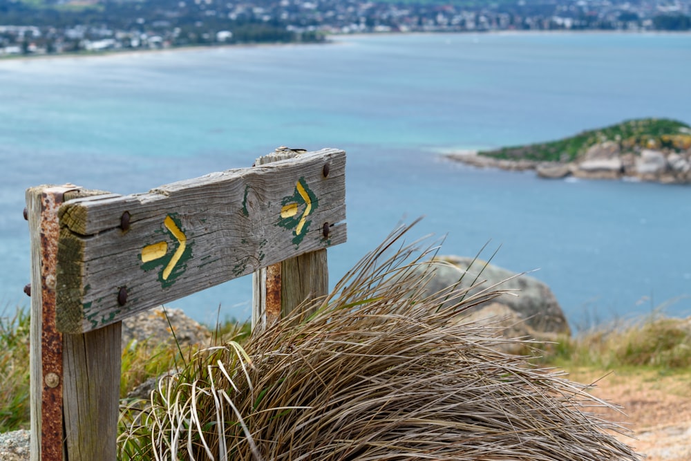 a wooden sign sitting on top of a lush green hillside