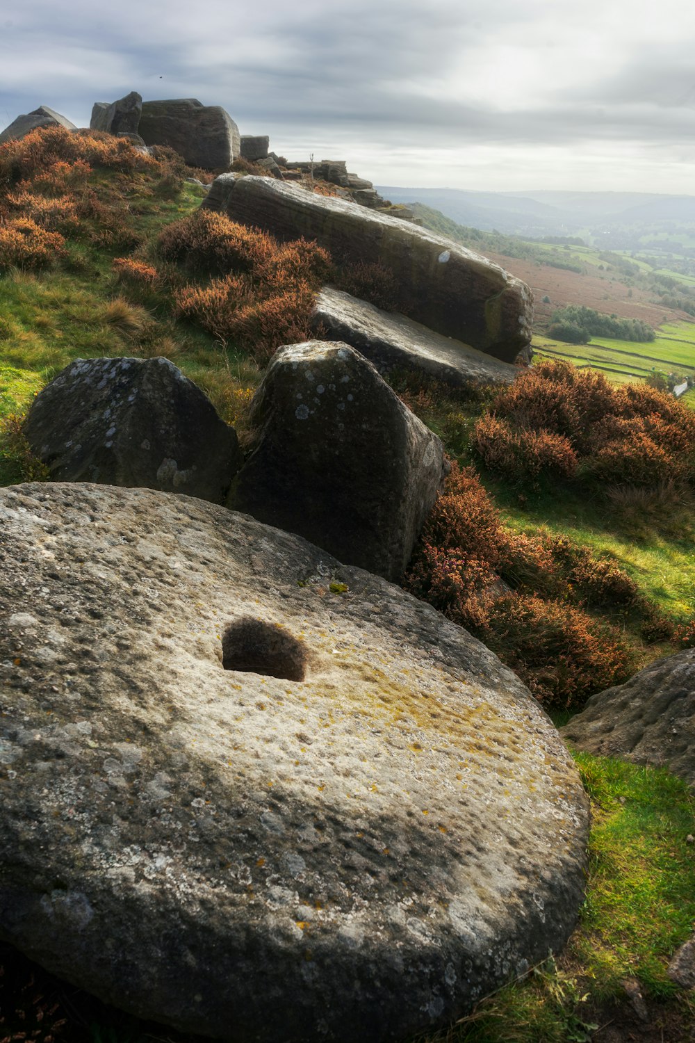 a large rock sitting on top of a lush green hillside