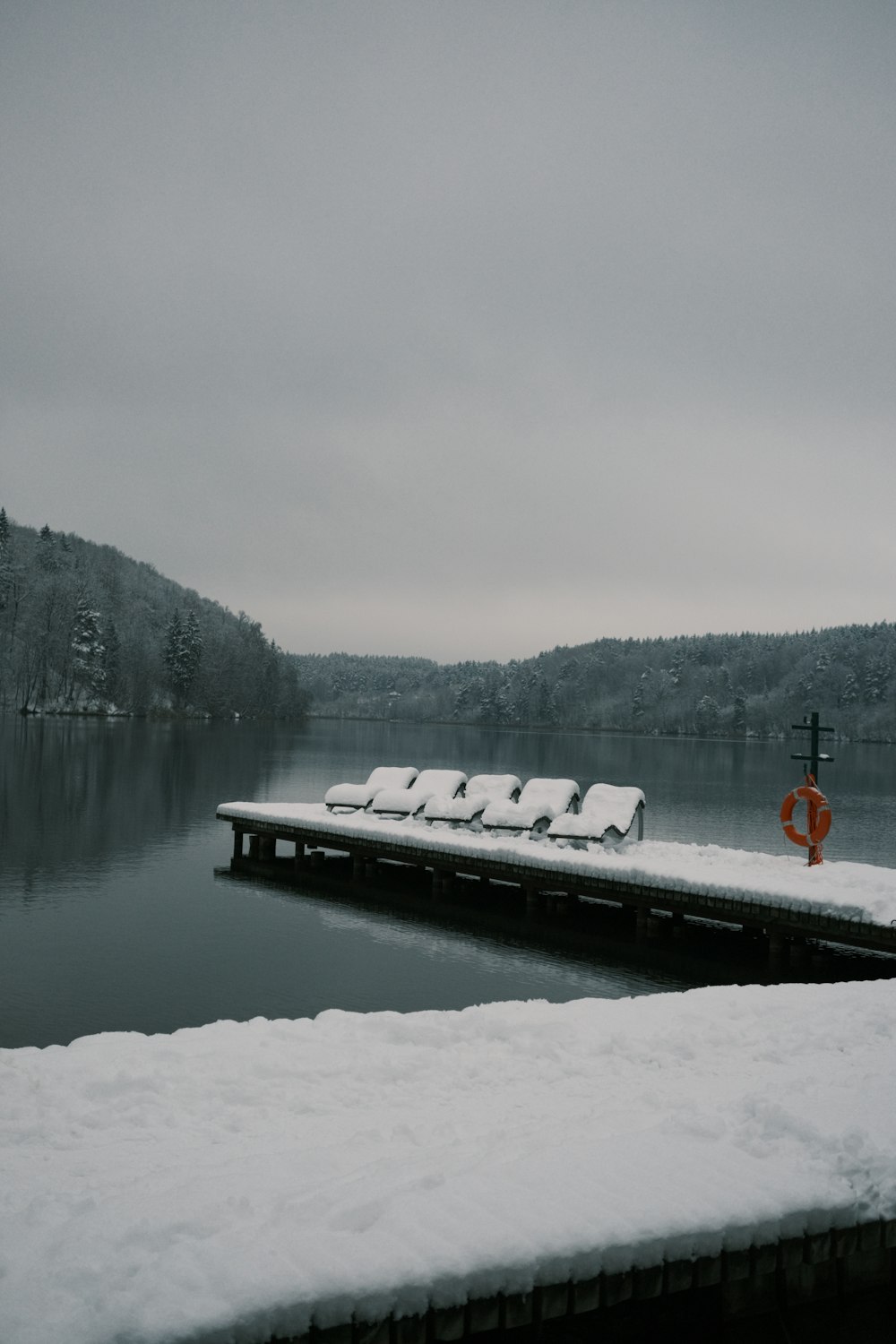 a dock covered in snow next to a body of water