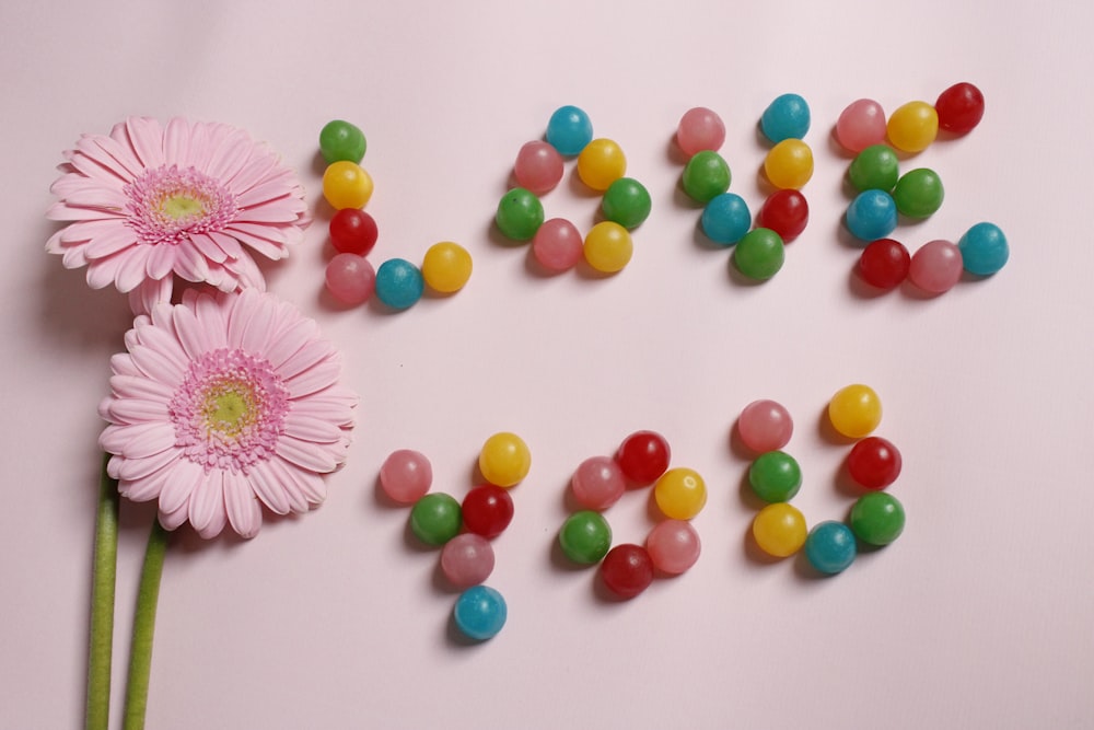 a pink flower next to a word made out of candy