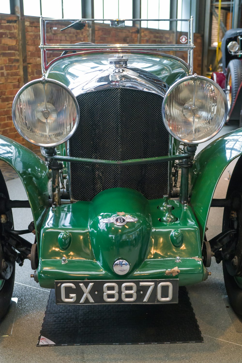 an old green car is parked in a garage