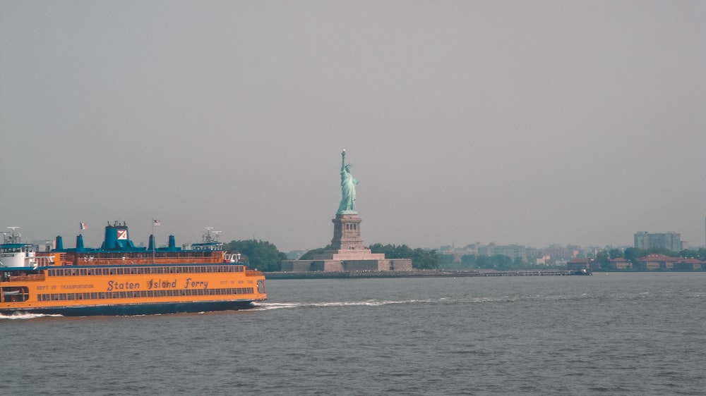 a large boat in the water near a statue of liberty