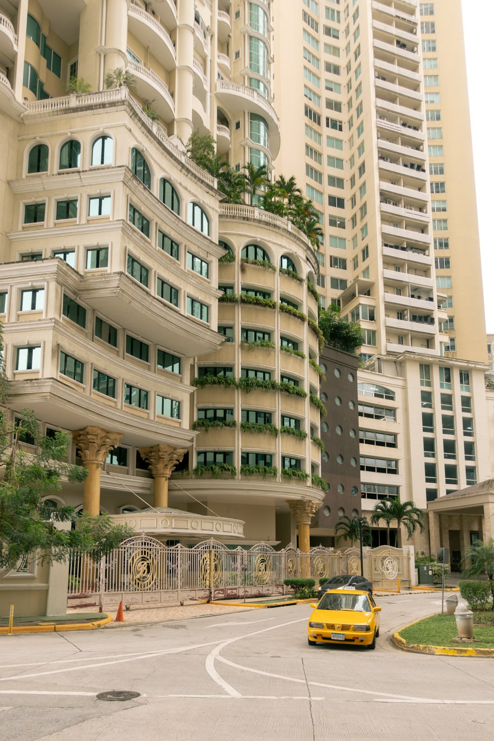 a yellow car driving past a tall building