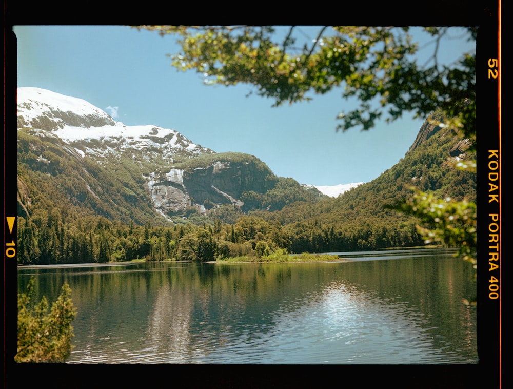 a lake surrounded by mountains with a snow covered mountain in the background