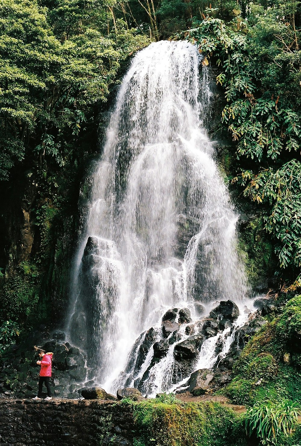 uma pessoa em pé em frente a uma cachoeira