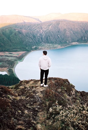 a man standing on top of a hill overlooking a lake