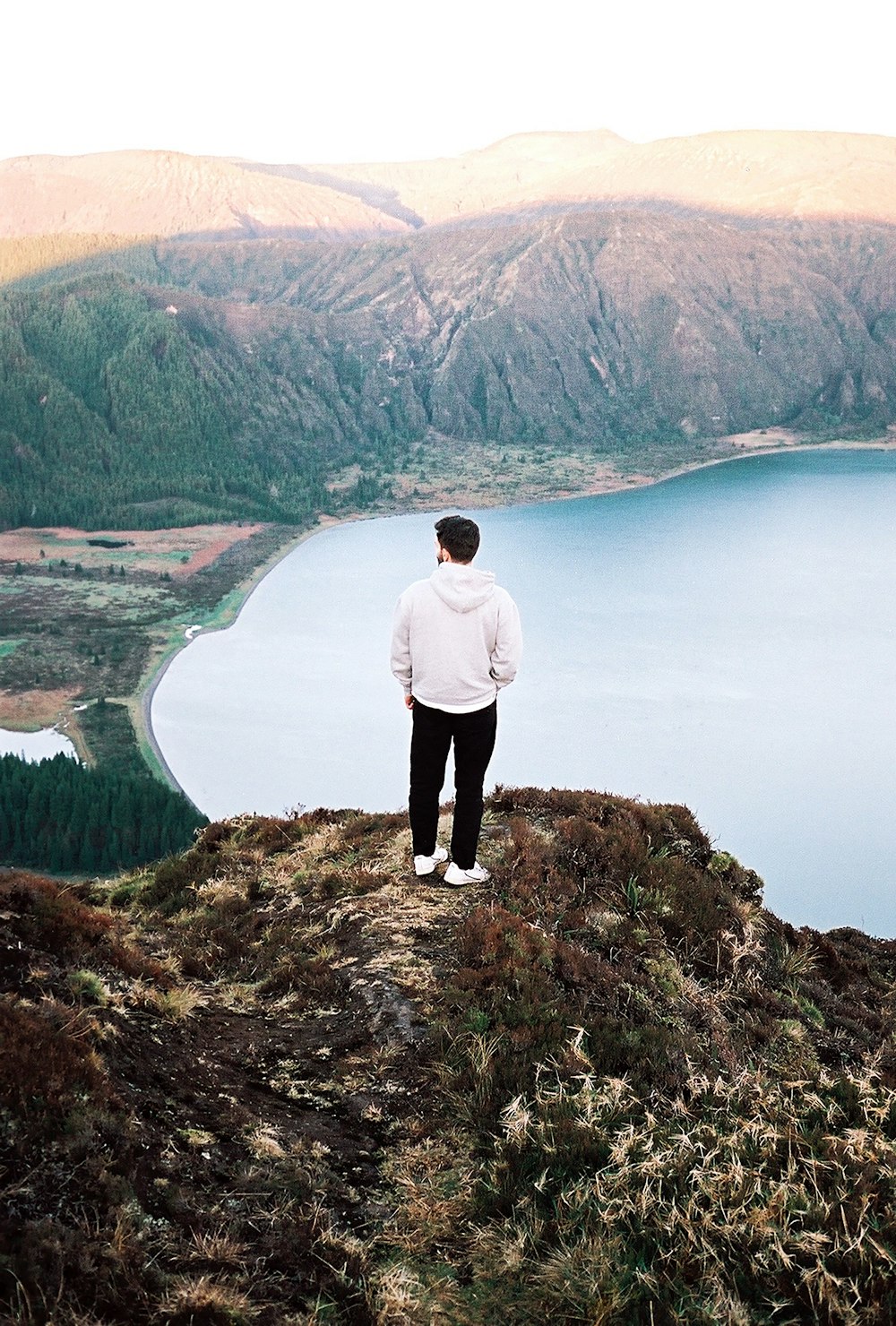 Un hombre de pie en la cima de una colina con vistas a un lago