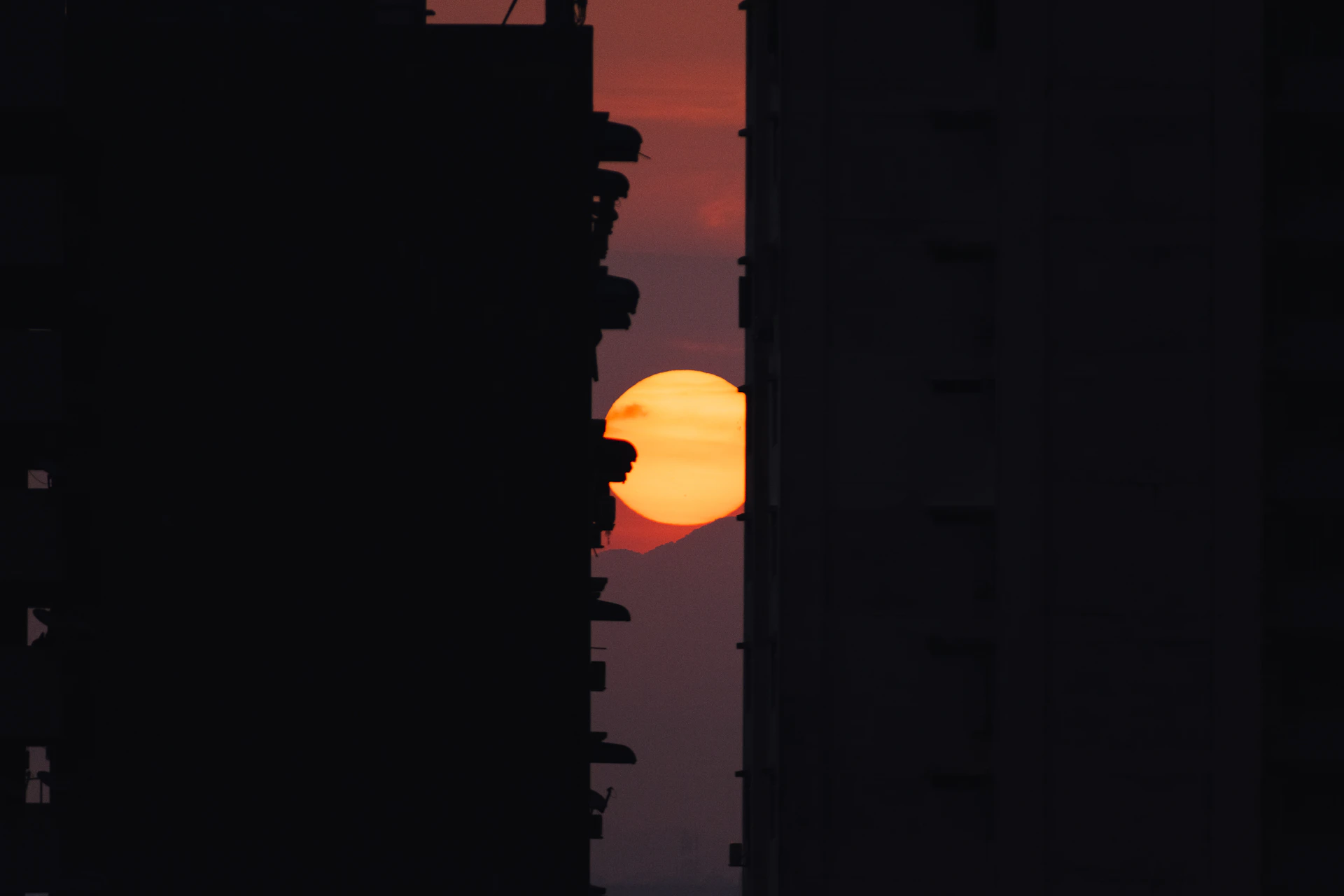 the sun is setting behind some tall buildings