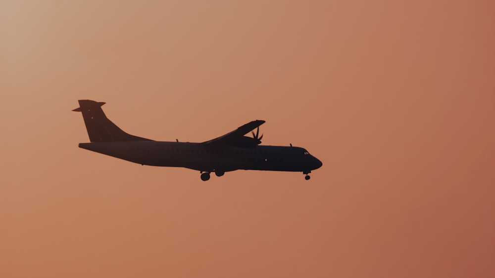 ein großes Flugzeug, das durch einen rosafarbenen Himmel fliegt