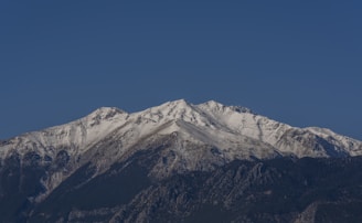 a snow covered mountain range under a blue sky