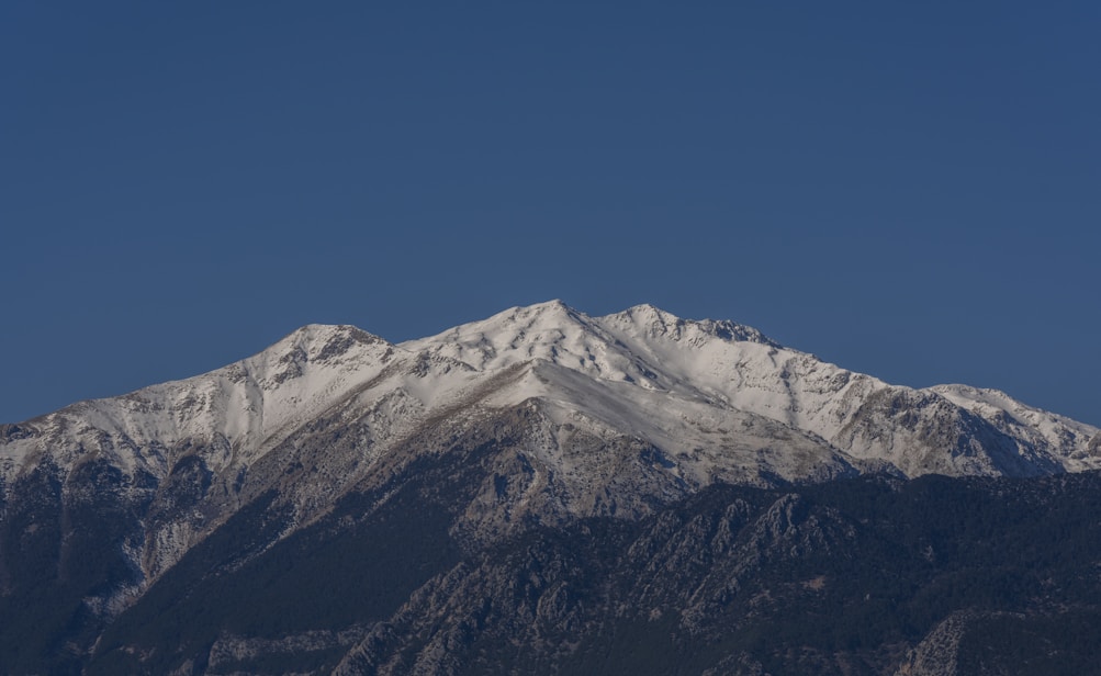 a snow covered mountain range under a blue sky