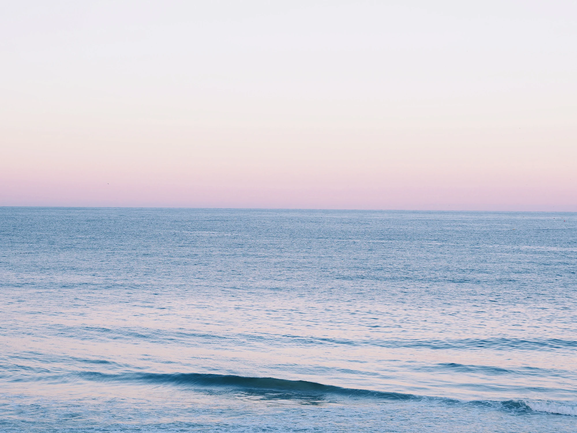 A calm body of water under a pink sky
