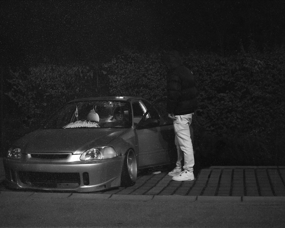 a man standing next to a parked car