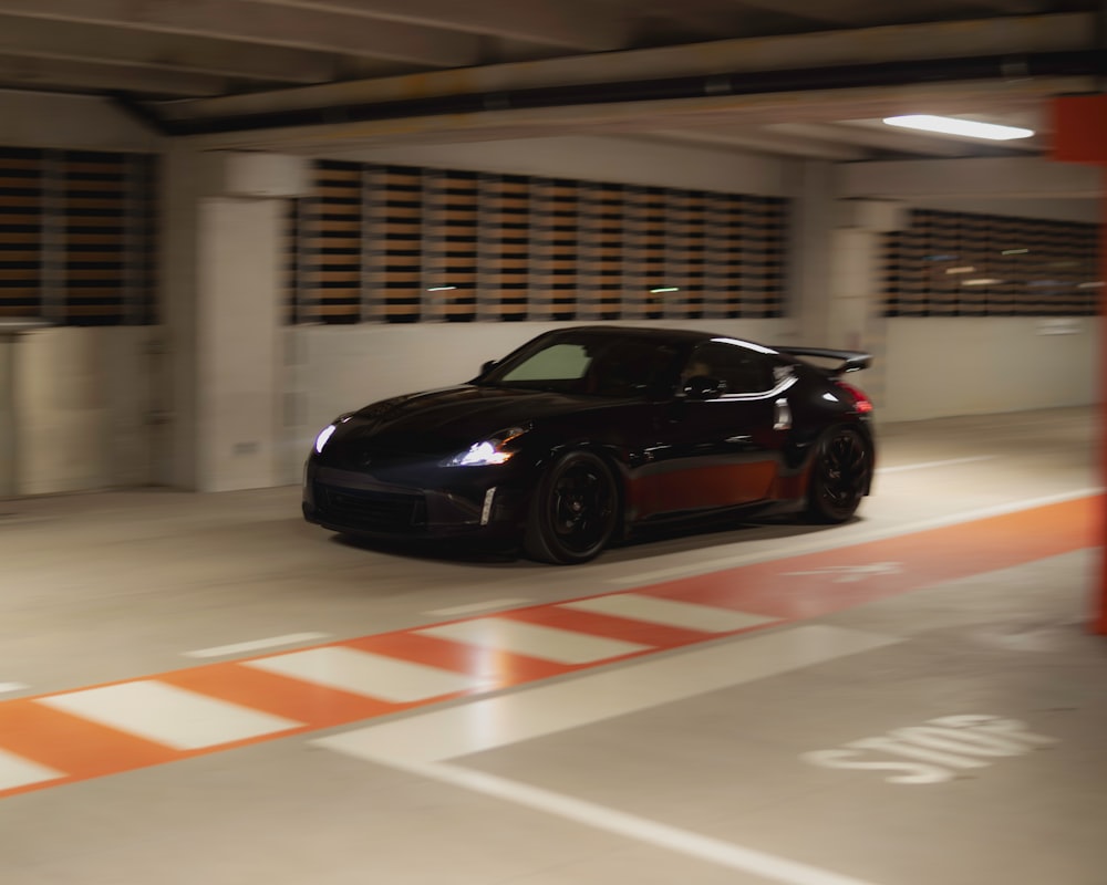 a black sports car driving through a parking garage