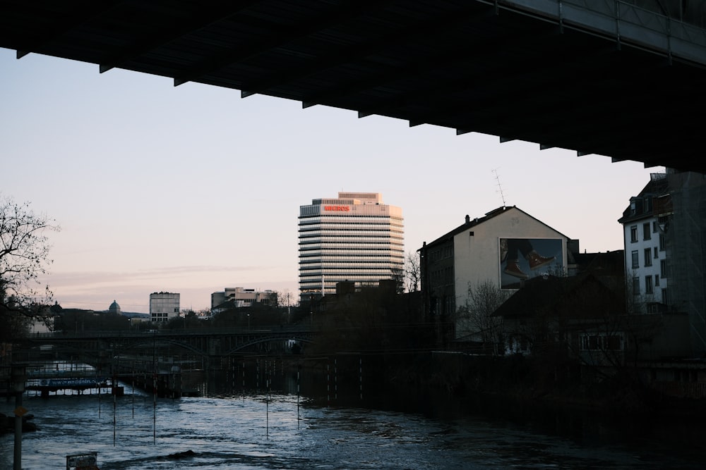 a river under a bridge with buildings in the background