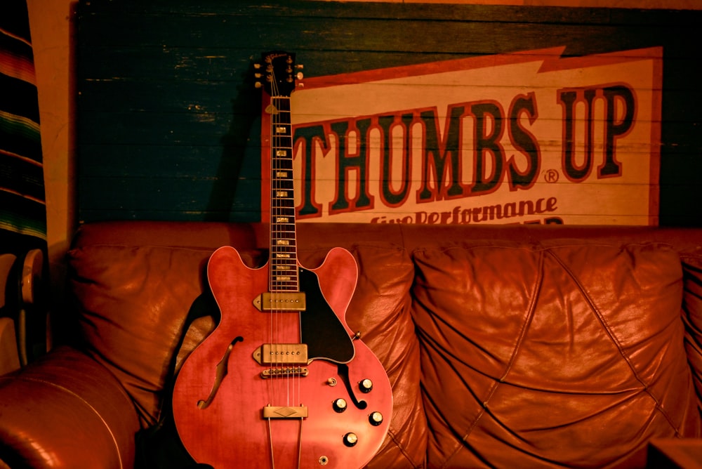 a red guitar sitting on top of a brown couch