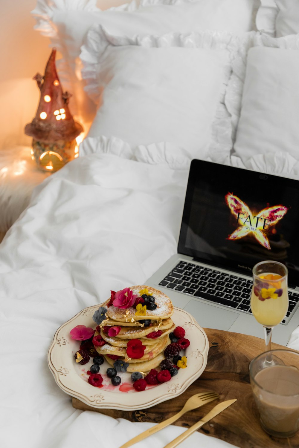 a plate of pancakes and a glass of champagne on a bed